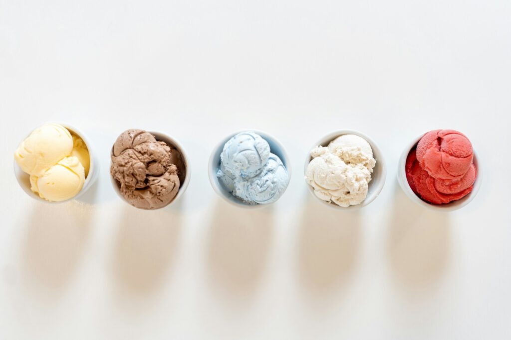 A row of 5 small tubs of assorted ice cream flavours.
